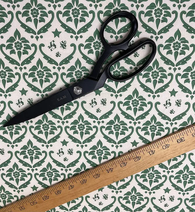 Scissors resting on a length of green fabric